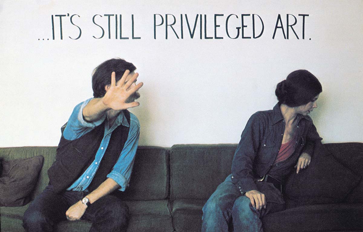 Un homme et une femme assis sur un sofa se détournant de la caméra avec le texte «… It’s still privileged art » au-dessus d’eux.  