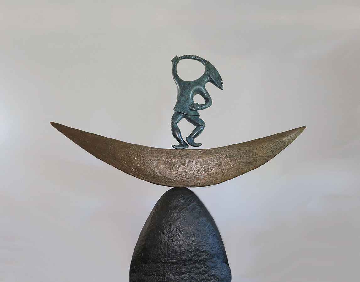 Sculpture de bronze montrant une figurine dansant sur un croissant de lune stylisé. 
