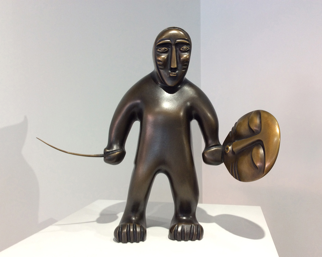 Sculpture de bronze montrant une figurine tenant un tambour et une baguette de tambour.  