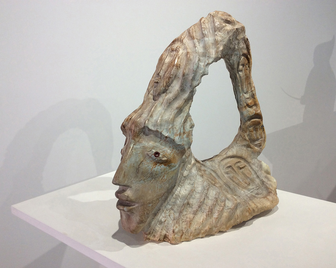 Sculpture en pierre à savon avec des visages gravés.  