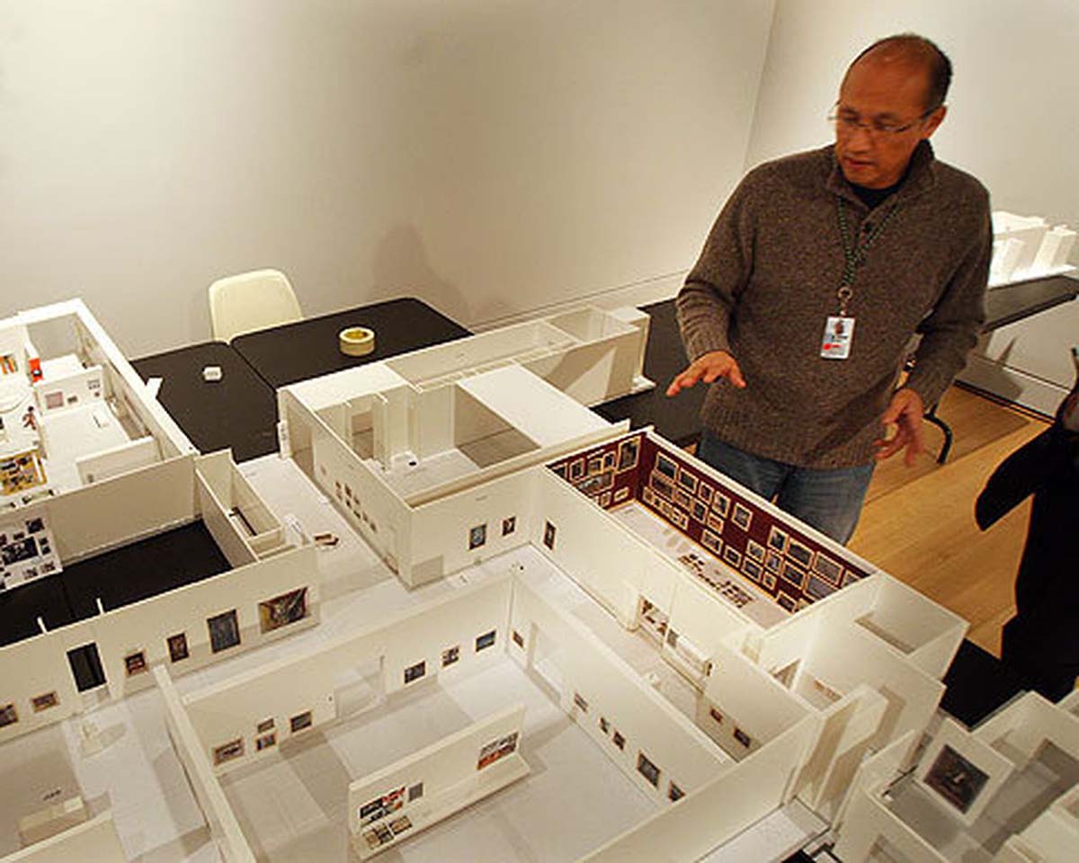 Un homme se tient devant des maquettes de salles d’exposition. 