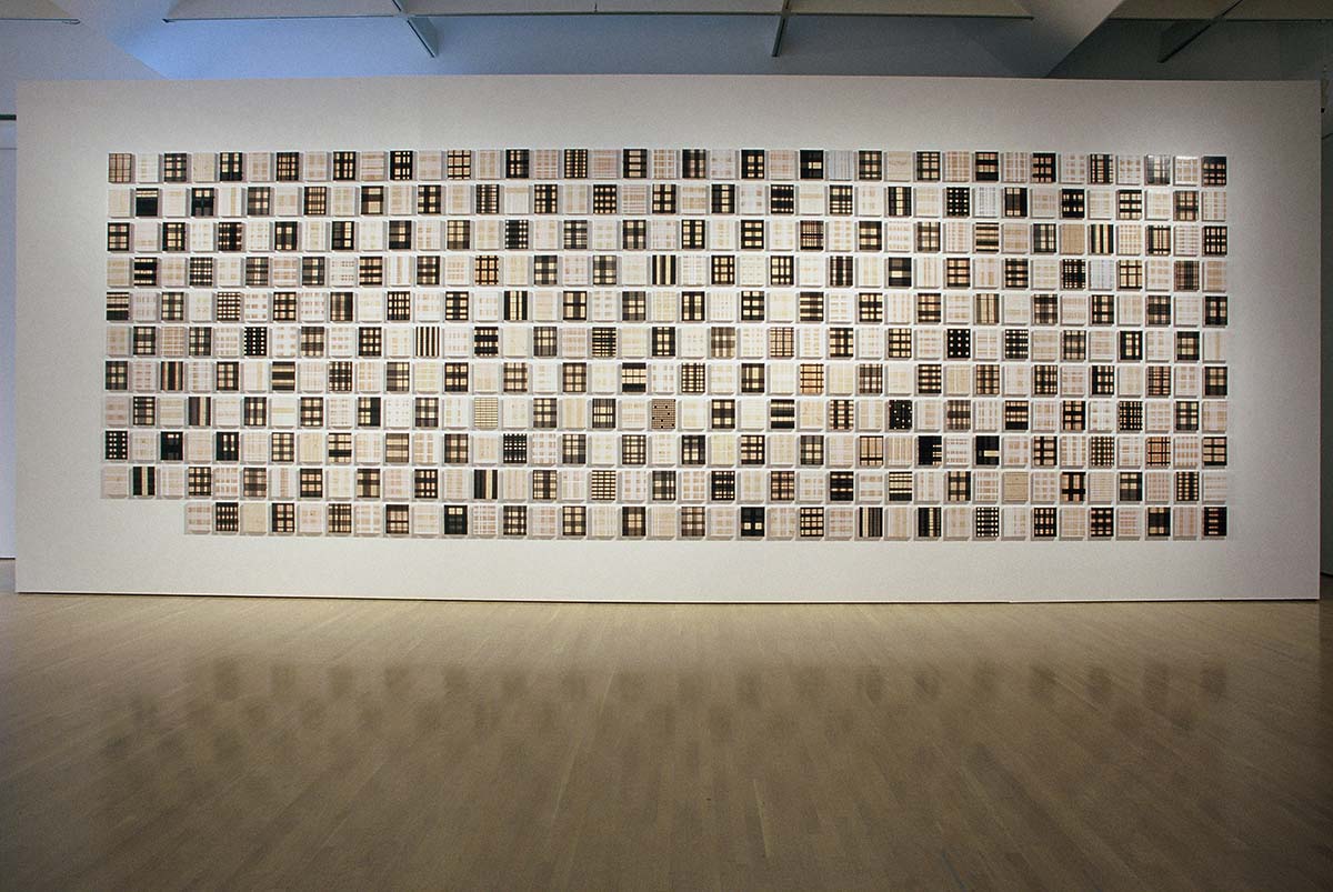 426 tableautins formant un quadrillage placés sur un mur dans une salle d’exposition.  