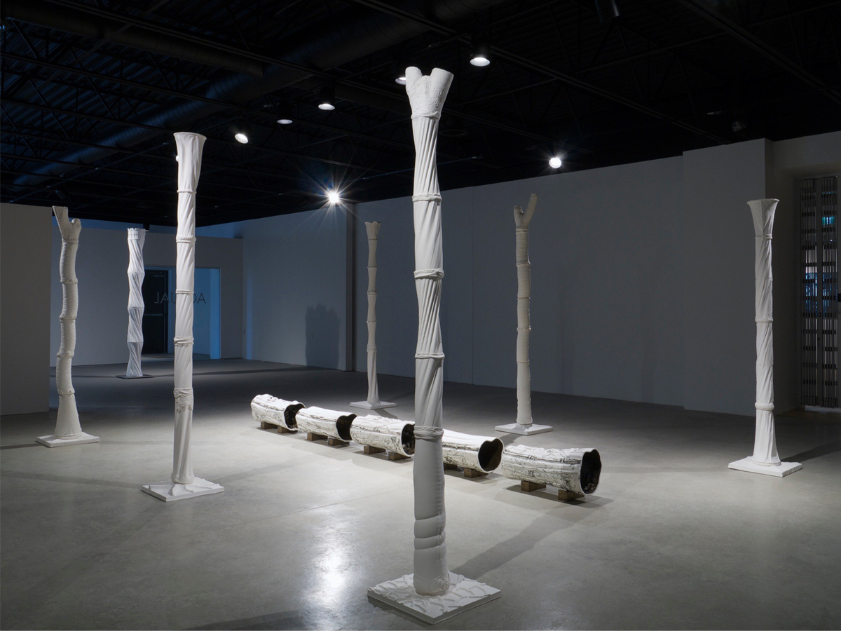 Six colonnes longues et minces faites en porcelaine non glacée, ponctuées de jointures horizontales et émergeant de plaques carrées. 