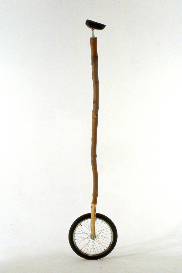 Monocycle constitué d’un long bâton de bois, et équipé d’une petite selle noire. 