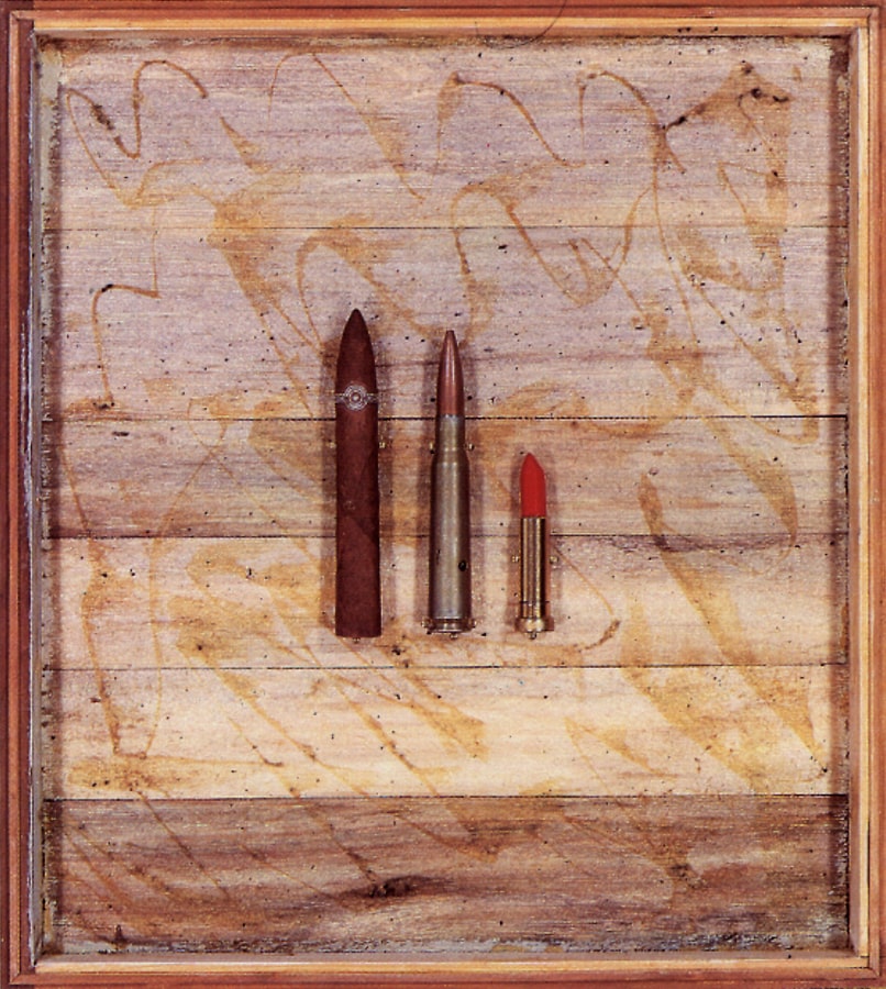 Une boîte en bois contenant un cigare, une balle de fusil, et un bâton de rouge à lèvres. 