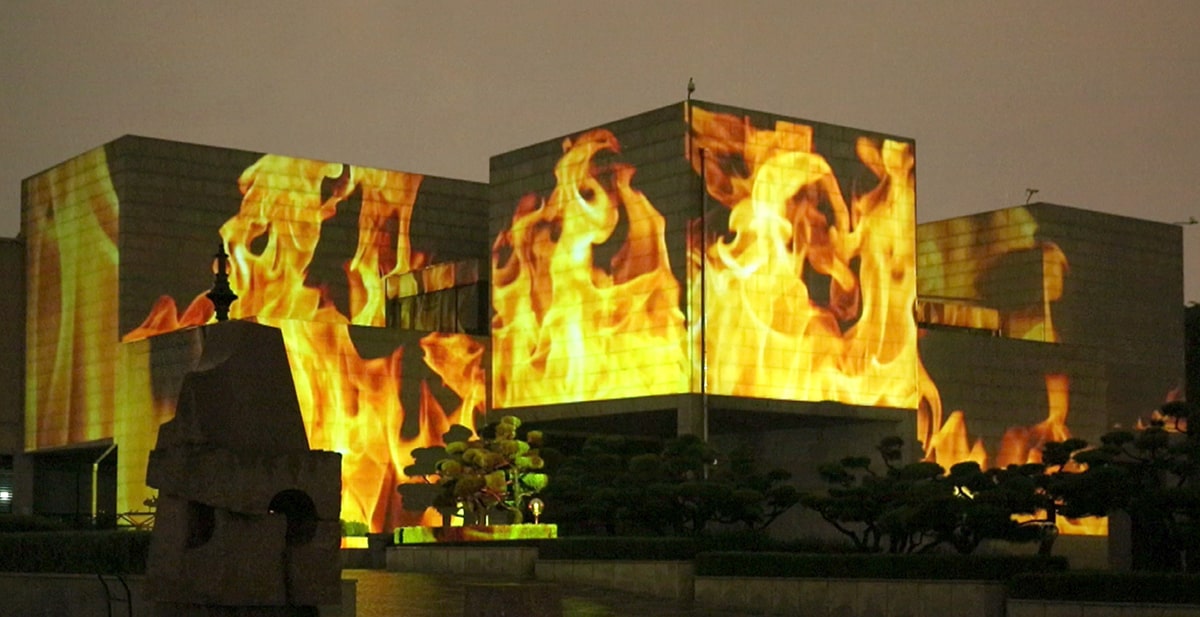 Plusieurs bâtiments sur lesquels sont projetées des images de flammes.  
