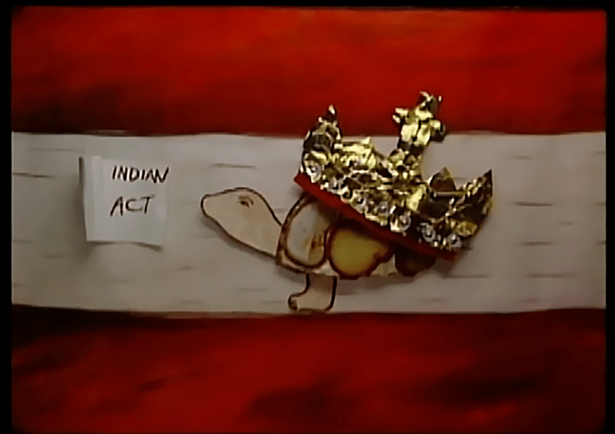 Un morceau d’écorce, une tortue en bois et un morceau d’or à côté d’un papier sur lequel est écrit « Indian Act ».  